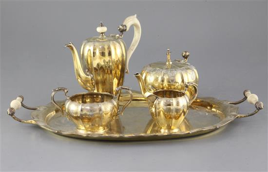 A George V silver gilt three piece coffee set and matching two handled oval tray, with later matched teapot, gross weight 74 oz.